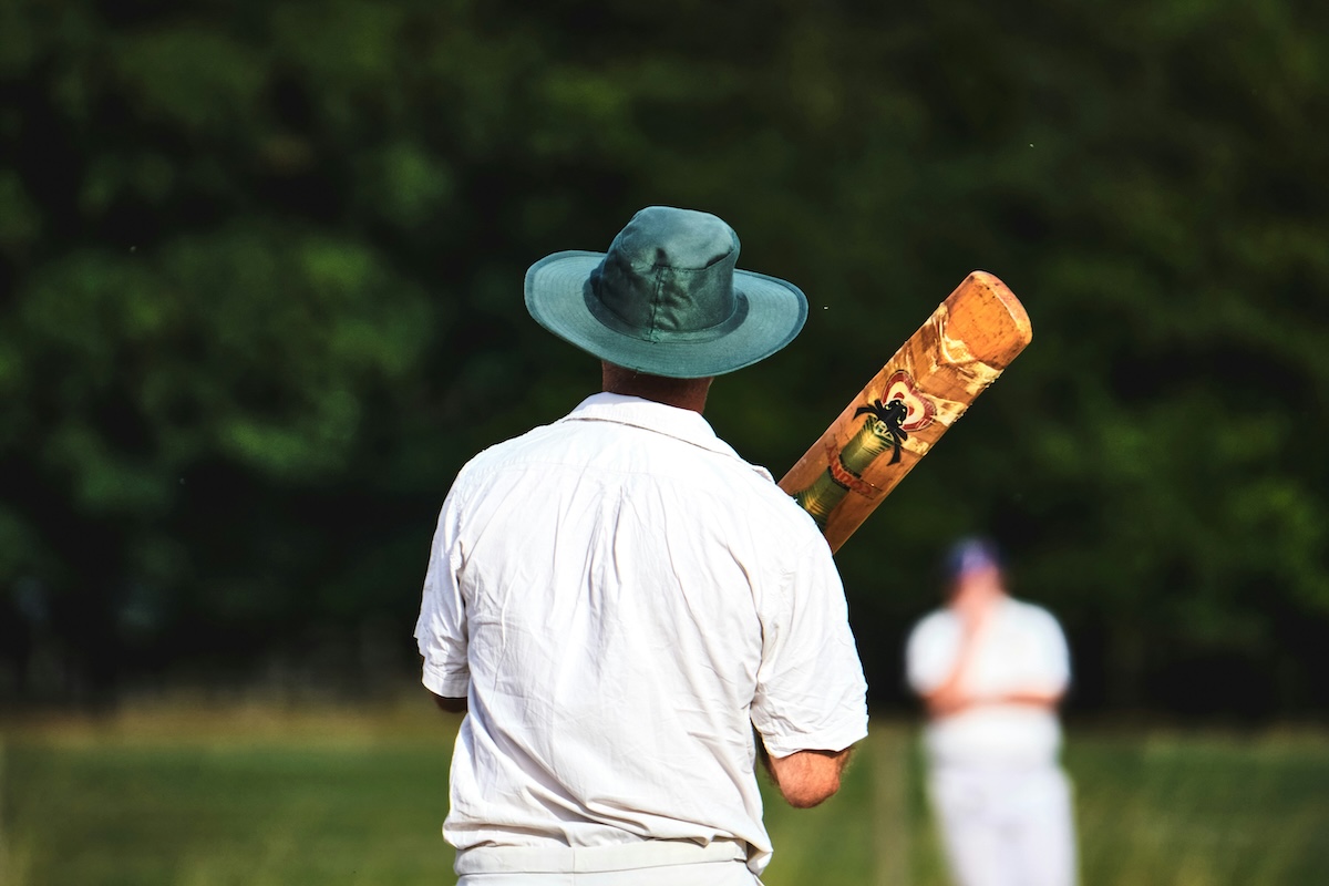 Man standing in a field holding a cricket bat