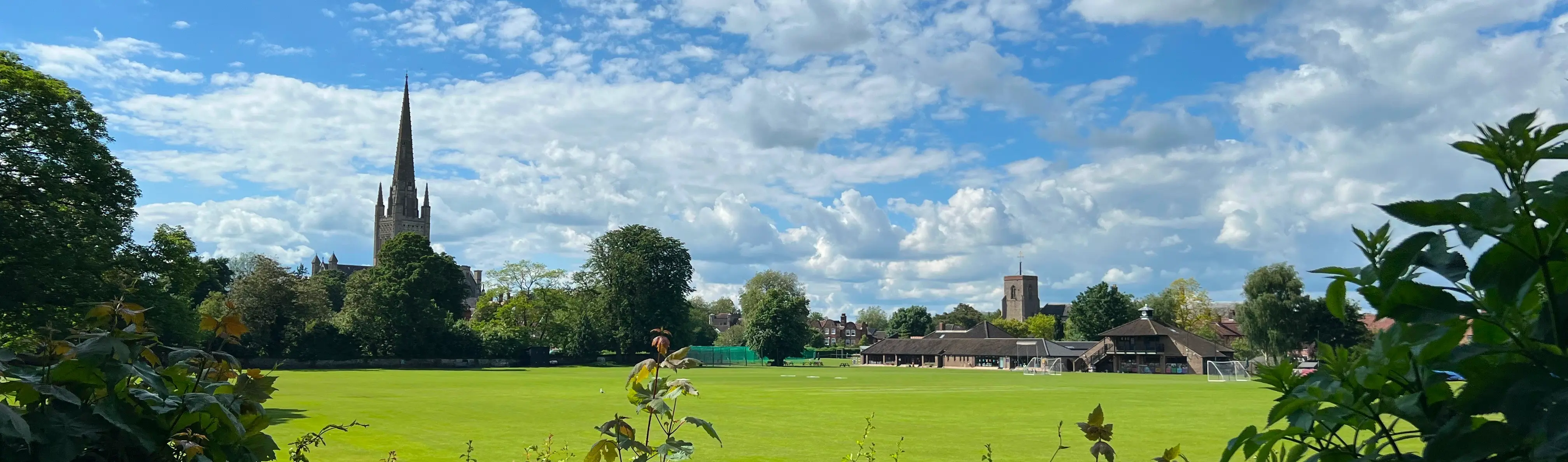 A field with football nets, with Norwich Cathedral in the background.